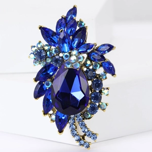 Detail of vintage style brooch with dark blue pear-shaped crystal and antique gold alloy base