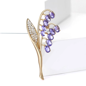 Dettaglio macro spilla mughetto con pietre viola e strass bianchi brillanti