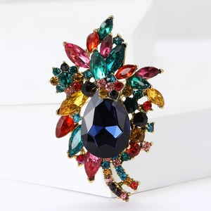 Macro detail of alloy brooch featuring a large pear-shaped blue stone and colorful gems