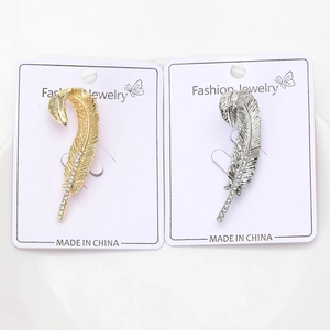 Detail view of gold and silver feather earrings with sparkling rhinestones on display card
