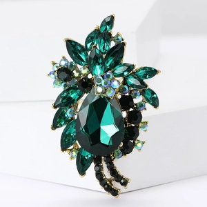 Close-up of vintage flower brooch with large green teardrop gem and shiny crystals