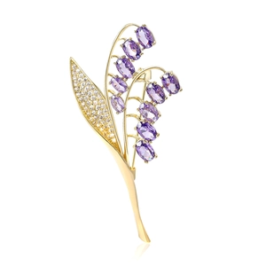 Elegante spilla a mughetto dorata con gemme viola e cristalli bianchi lucidi