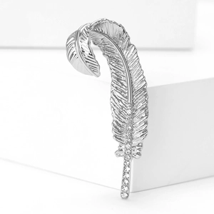 Close-up of vintage silver feather brooch with sparkling zircons and brushed texture