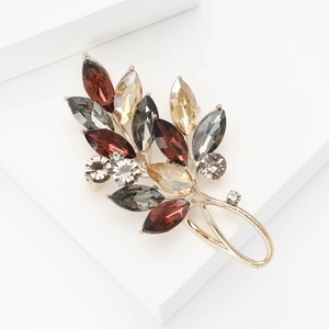 Broche élégante en feuille d'or avec cristaux champagne sur un support blanc pur