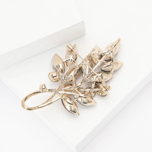 Détail de la structure arrière d'une broche feuille dorée avec pierres rouges serties