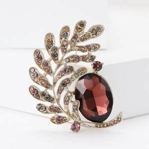 Elegant gold leaf and moon brooch with colorful rhinestones and a red gemstone focal point