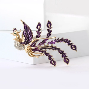 Detail of gold-plated phoenix brooch with purple enamel wings and sparkling rhinestones
