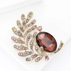 Elegant gold leaf brooch with rhinestones and a large burgundy gemstone center
