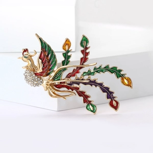 Detailed macro view of colorful enamel phoenix brooch with white rhinestones and gold plating