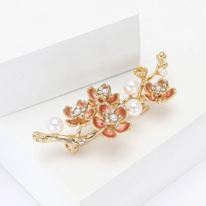 Eleganter Pflaumenblüten-Brosche in Gold mit rosa Blüten und Perlen auf weißem Grund