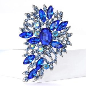 Makroaufnahme einer Brosche aus Silberlegierung mit blauem Kristall und Strass-Blüten