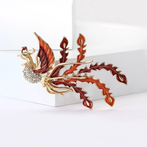 Elegant phoenix brooch with red enamel wings and sparkling crystals on golden metal base
