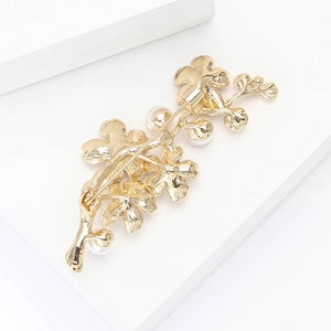 Nahaufnahme der eleganten Blumenast-Brosche mit Rücknadel und Perlen-Details auf Gold