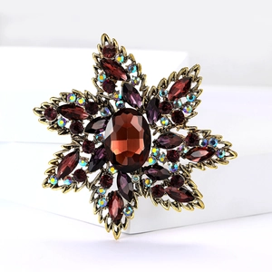 Detail of vintage flower brooch with deep red crystal and iridescent rhinestones