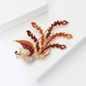 Elegant phoenix brooch with red enamel wings and sparkling crystals on golden base