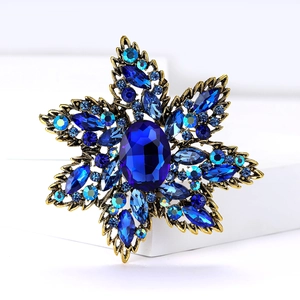 Macro view of a luxury vintage gold snowflake brooch with deep blue rhinestones