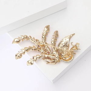 Detailed view of the gold Phoenix brooch featuring intricate leaf textures and rhinestones