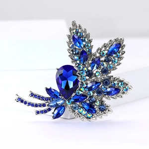 Macro shot of silver alloy leaf brooch with blue rhinestones and crystal fire details