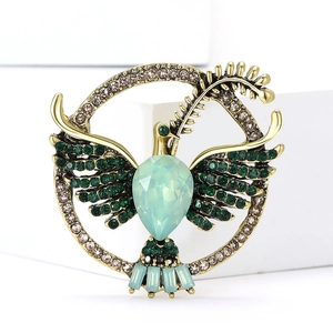 Detail of vintage gold bird brooch with green rhinestones and olive branch in circle