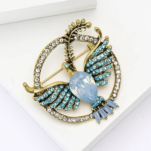Elegant gold-tone dove brooch with sky blue crystals and central drop-shaped opal gem