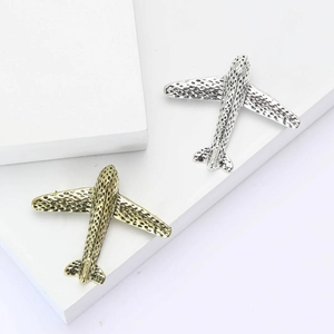 Polished silver and vintage gold airplane brooches on geometric pedestals