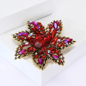 Vintage red rhinestone floral brooch with antique gold finish on white podium