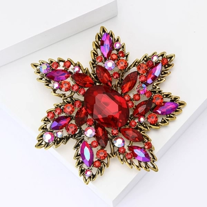 Vintage gold star brooch with red ruby stones and purple rhinestones on white stand