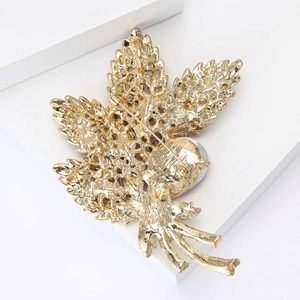 Detailed back view of golden leaf brooch showing hollow craft and pin fastening mechanism