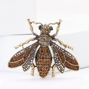 Detailed macro of a vintage golden bee brooch with sparkling crystals on white stand