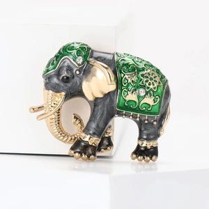 Detailed macro shot of vintage enamel elephant brooch with green floral patterns