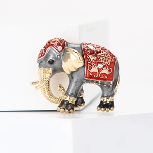 Vintage enamel elephant brooch with red floral pattern and crystal accents on a white stand
