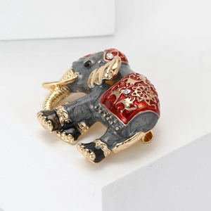Macro shot of Thai style elephant brooch with grey enamel and red saddle on white pedestal