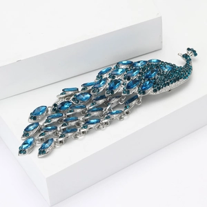 Élégante broche paon avec cristaux de strass bleus étincelants sur un socle blanc