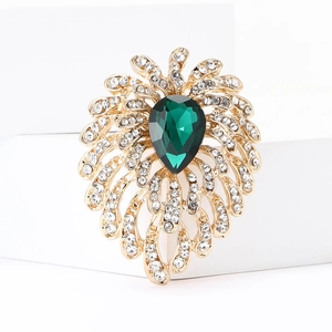 Elegant gold fireworks brooch with pear-shaped green gemstone and sparkling rhinestones