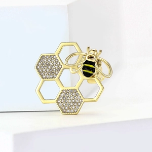 Détail d'une broche abeille dorée avec alvéoles de miel et cristaux scintillants