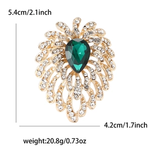 Elegant rhinestone fireworks brooch with a large pear-shaped green gemstone in center