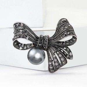 Vintage silver bow brooch with grey rhinestones and a large pearl on white stone