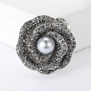Macro detail of retro rose brooch with grey rhinestones and large dark grey pearl