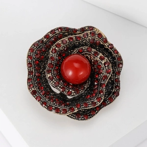 Vintage rose flower brooch with red rhinestones and a central bead on bronze base