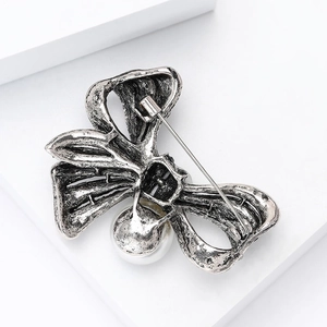 Detail view of vintage silver bow brooch back with secure safety pin and white pearl drop