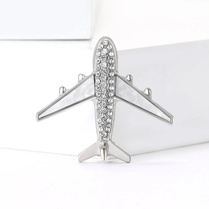 Silver airplane brooch with sparkling crystals and mother of pearl inlay on white base