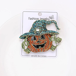 Detailed close-up of a pumpkin brooch with orange rhinestones and a blue witch hat