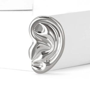 Macro shot of silver alloy ear-shaped brooch with a polished mirror finish on white block