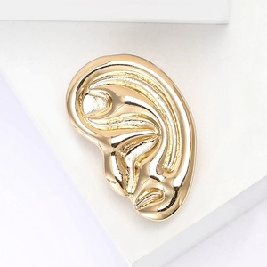 Minimalist gold-finish ear-shaped alloy brooch for women coats on a geometric stand