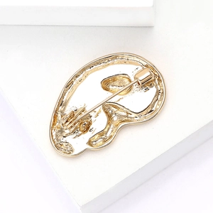 Close-up of golden ear-shaped alloy brooch showing back pin and safety lock mechanism