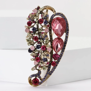 Detailed macro of vintage alloy leaf brooch with colorful rhinestones and pink water drops