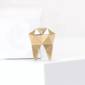 Minimalist geometric gold tooth brooch with a polished 3D faceted metallic finish