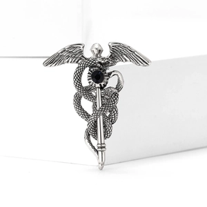 Détail d'une broche Caducée en argent vintage avec ailes de serpent et pierre précieuse bleue