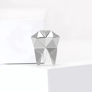Minimalist silver geometric tooth brooch with polished facets on white stone blocks