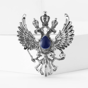 Macro detail of antique silver double-headed eagle brooch with blue drop gemstone